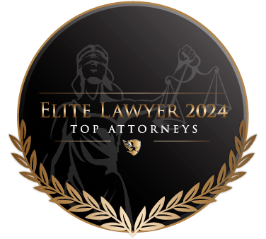 A round black and gold emblem with laurel leaves, featuring an illustration of Lady Justice and the text "Elite Lawyer 2024 Top Attorneys" at the center.