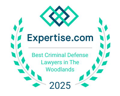 A badge from Expertise.com reads: "Best Criminal Defense Lawyers in The Woodlands 2025," surrounded by a laurel wreath and featuring a geometric logo at the top.